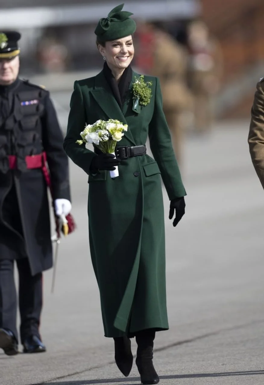Kate Middleton u dugom zelenom kaputu s buketom cvijeća.