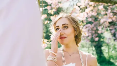Emotivna žena briše suzu u rascvjetanom parku tijekom proljeća.