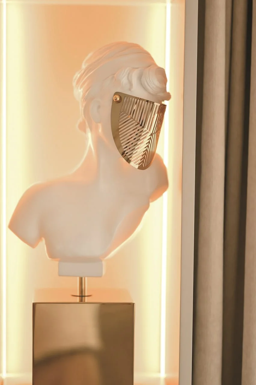 Bijela skulptura ljudskog poprsja sa zlatnom maskom na licu.