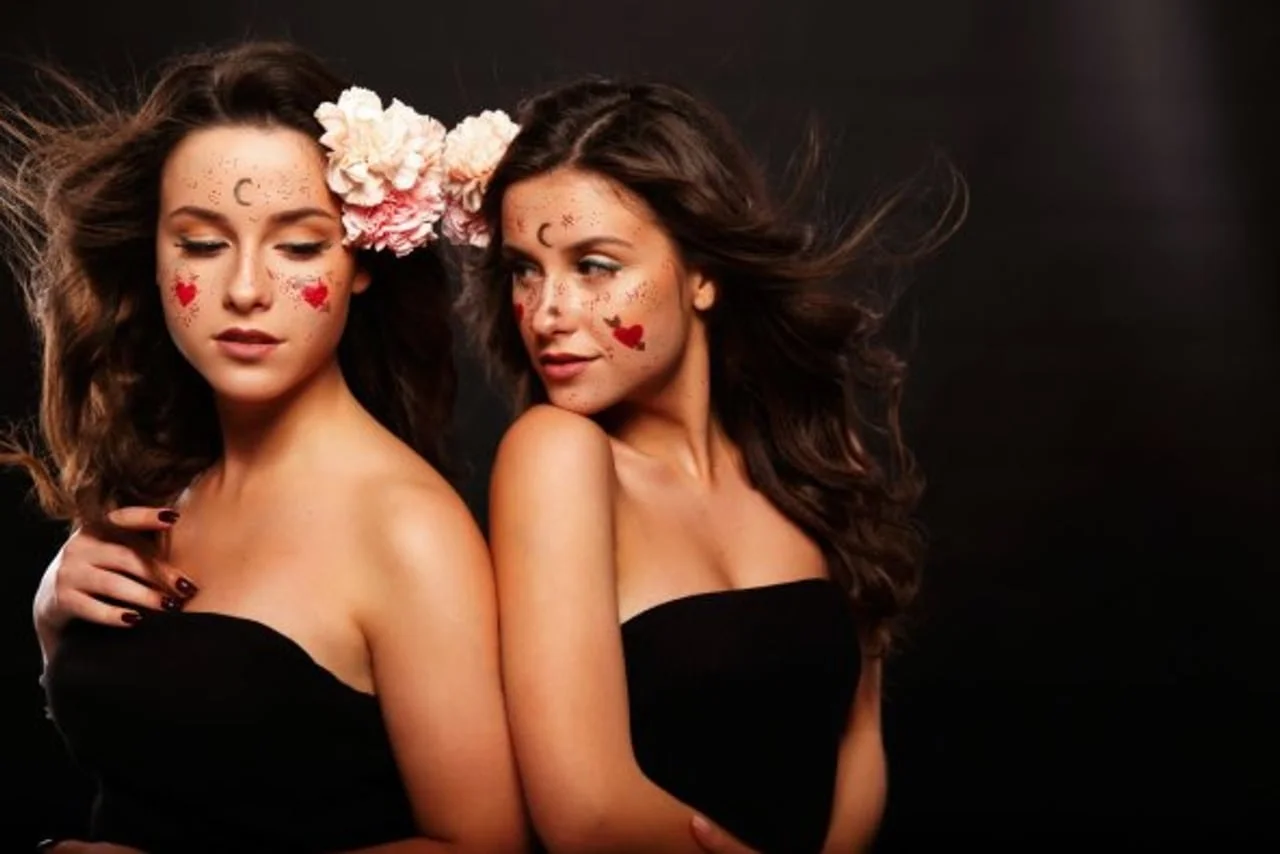 Dvije žene sa cvijećem u kosi i nacrtanim srcima na licu