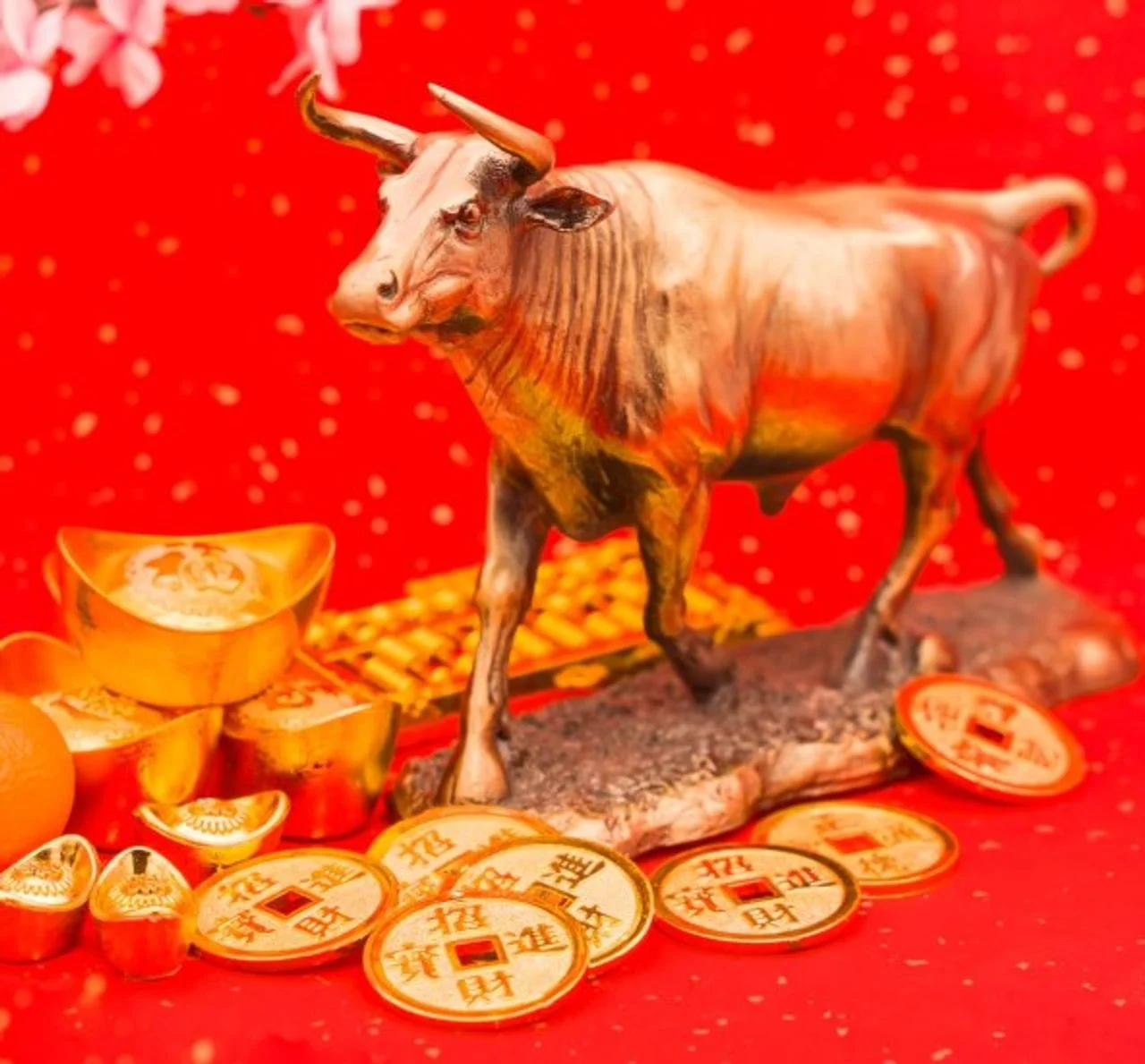 Brončani kip vola okružen zlatnim kineskim kovanicama sreće