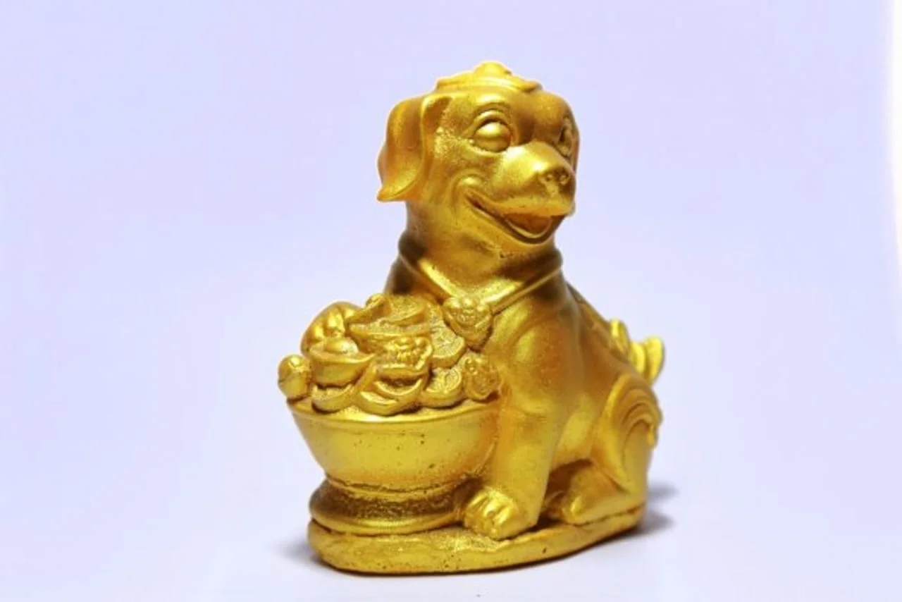 Zlatna figura psa koji sjedi pored posude s blagom