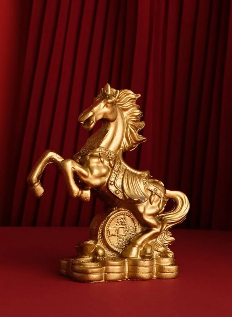 Zlatni kip konja na stražnjim nogama ispred crvene zavjese
