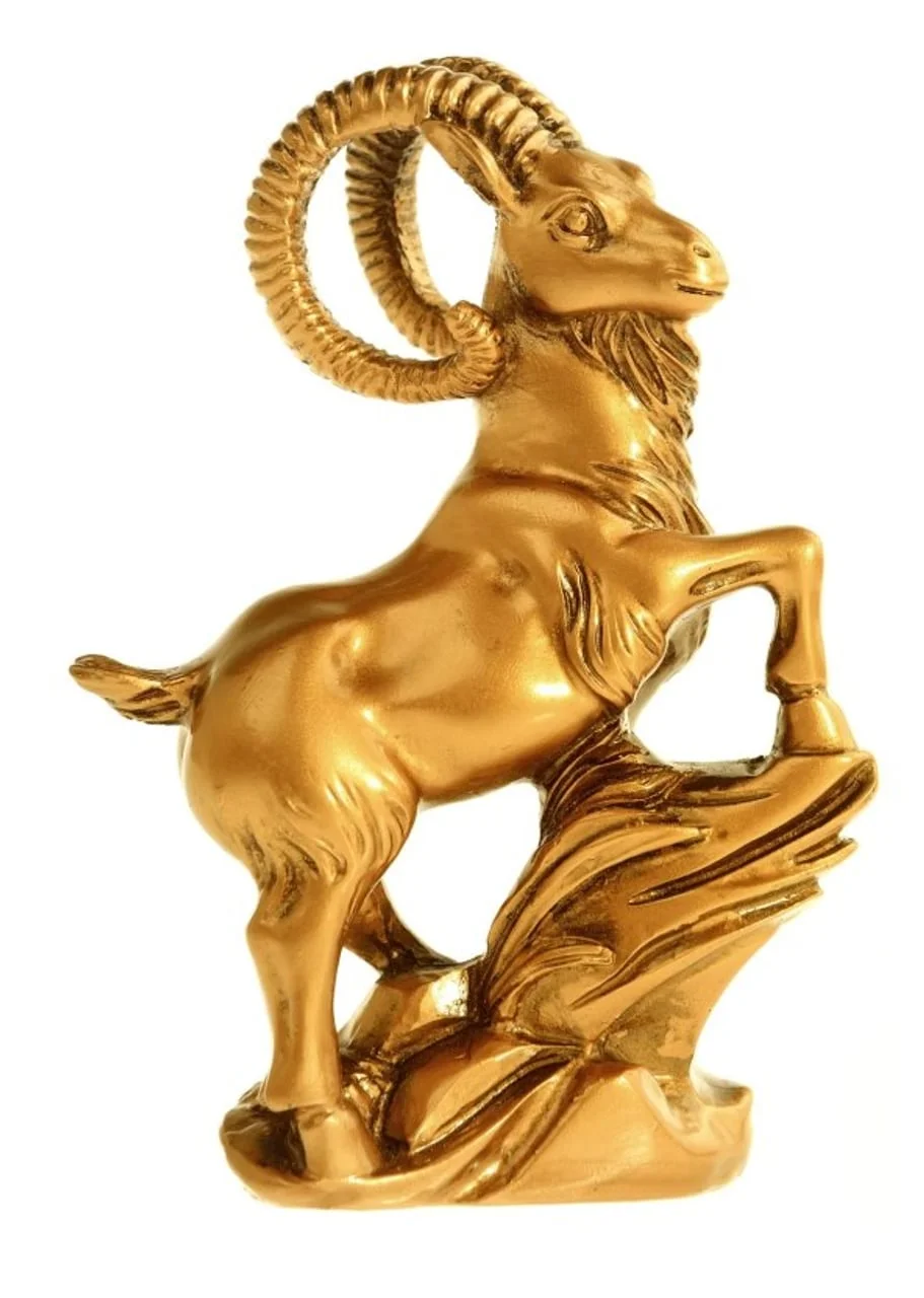Zlatna figura koze s velikim rogovima na bijeloj pozadini