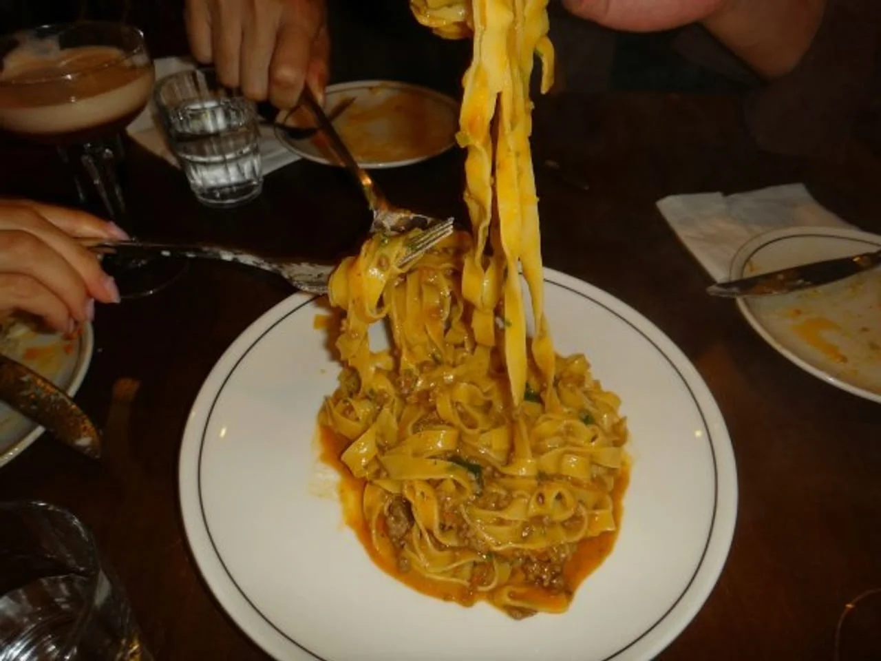 Tjestenina s mesnim umakom na bijelom tanjuru u restoranu