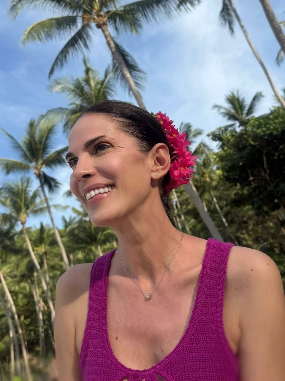 Glumica s ružičastim cvijetom u kosi na tropskoj pozadini