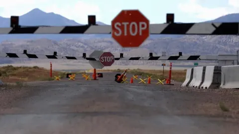 Zatvorena cesta sa znakom stop i rampom ispred planina.