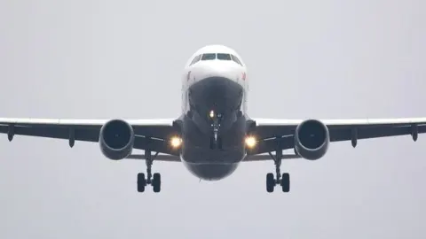 Veliki putnički zrakoplov snimljen sprijeda tijekom slijetanja s izvučenim kotačima.