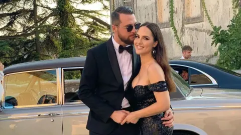 Lana Jurčević i Filip Kratofil poziraju u svečanoj odjeći ispred starog automobila.