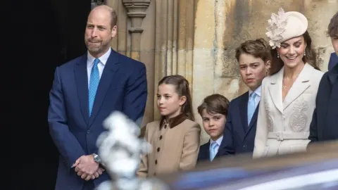 Princ William, Kate Middleton i djeca stoje ispred kamene crkve.