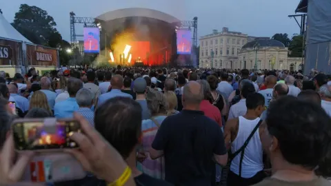 Velika masa ljudi prati koncert na otvorenom ispred osvijetljene pozornice.