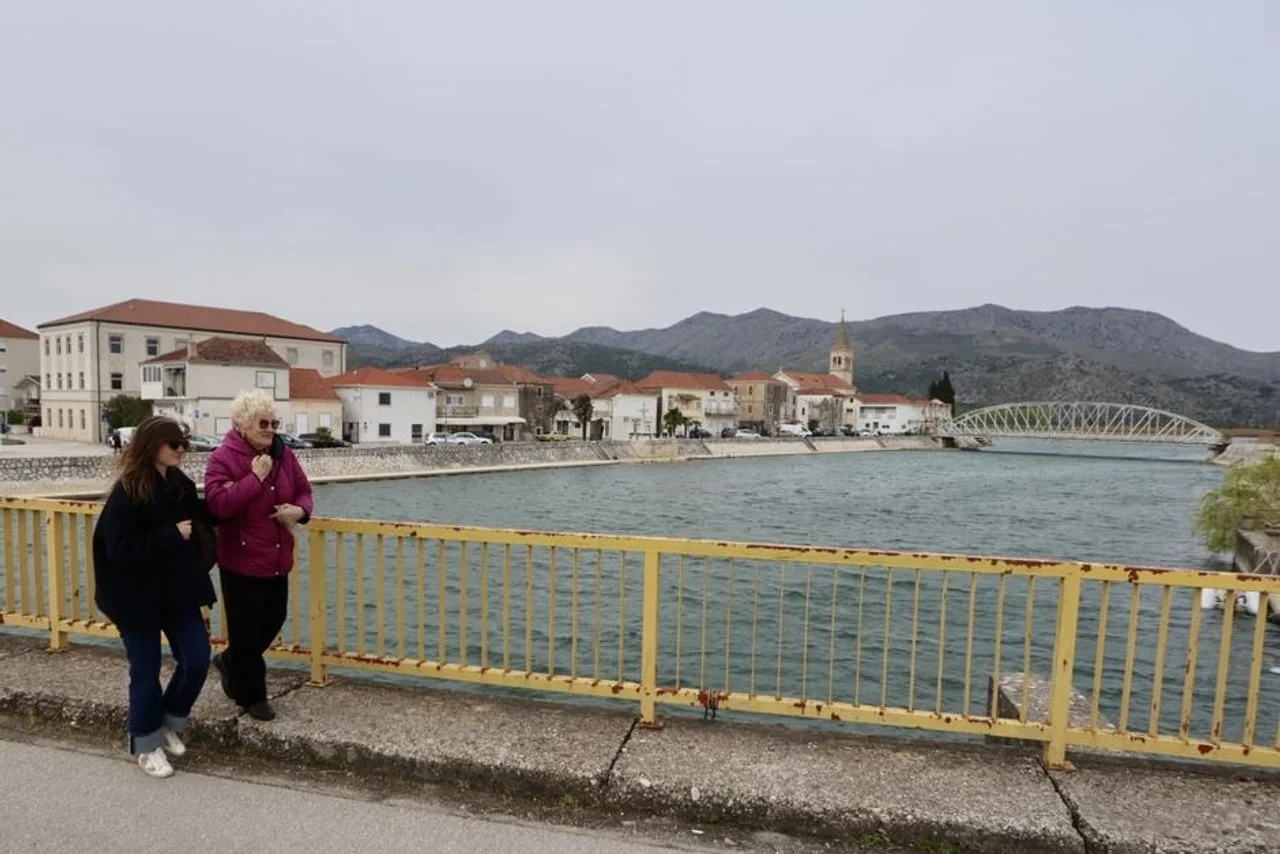 Dvije žene hodaju mostom preko rijeke Neretve u Opuzenu.