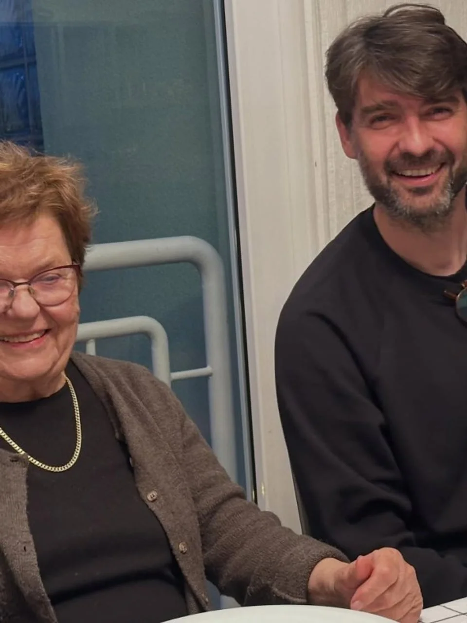 Vedran Ćorluka i starija gospođa sjede za stolom i smiju se.