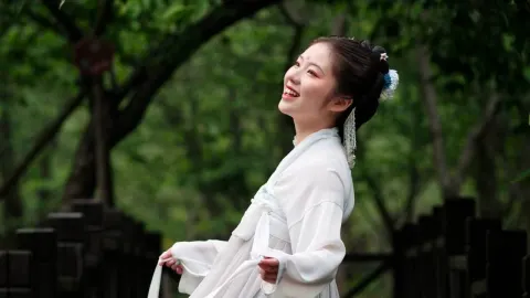 Nasmijana žena u tradicionalnoj bijeloj kineskoj odjeći na otvorenom