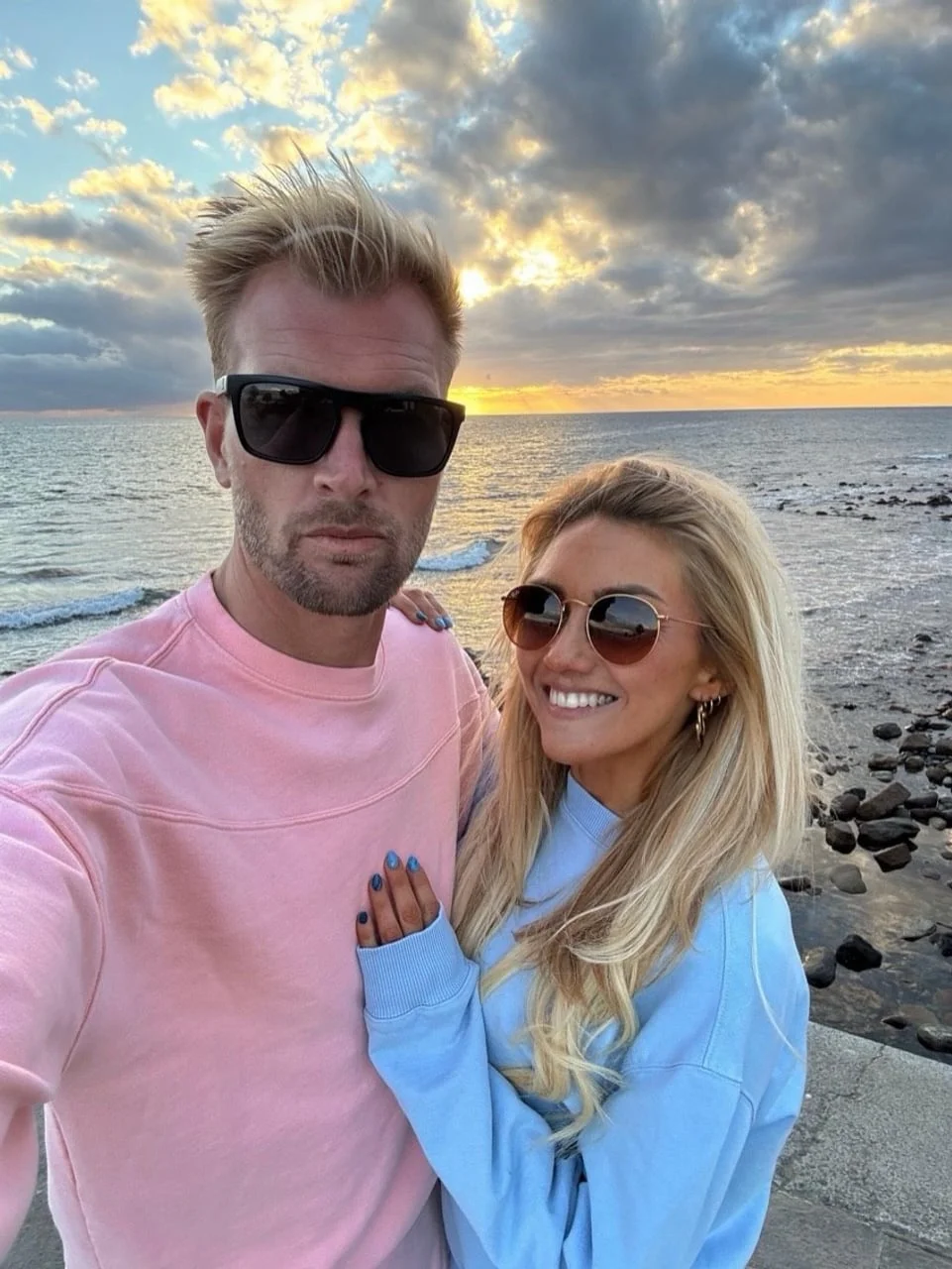 Ruben i Charlotte poziraju uz more tijekom zalaska sunca.