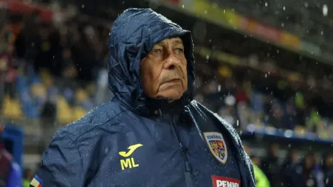Mircea Lucescu u kabanici na nogometnom stadionu pod kišom.