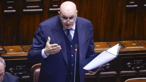 Talijanski ministar Guido Crosetto govori za govornicom u parlamentu s papirima u ruci.