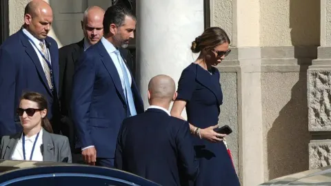 Donald Trump Junior u odijelu hoda u pratnji osiguranja i ženske osobe.