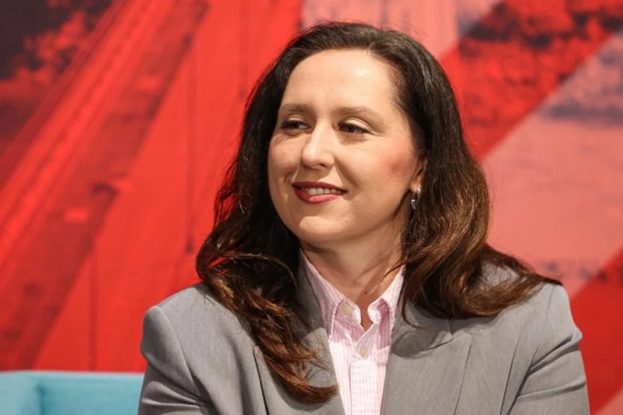 Portret nasmiješene Petre Škrobot u sivoj odjevnoj kombinaciji na crvenoj pozadini.