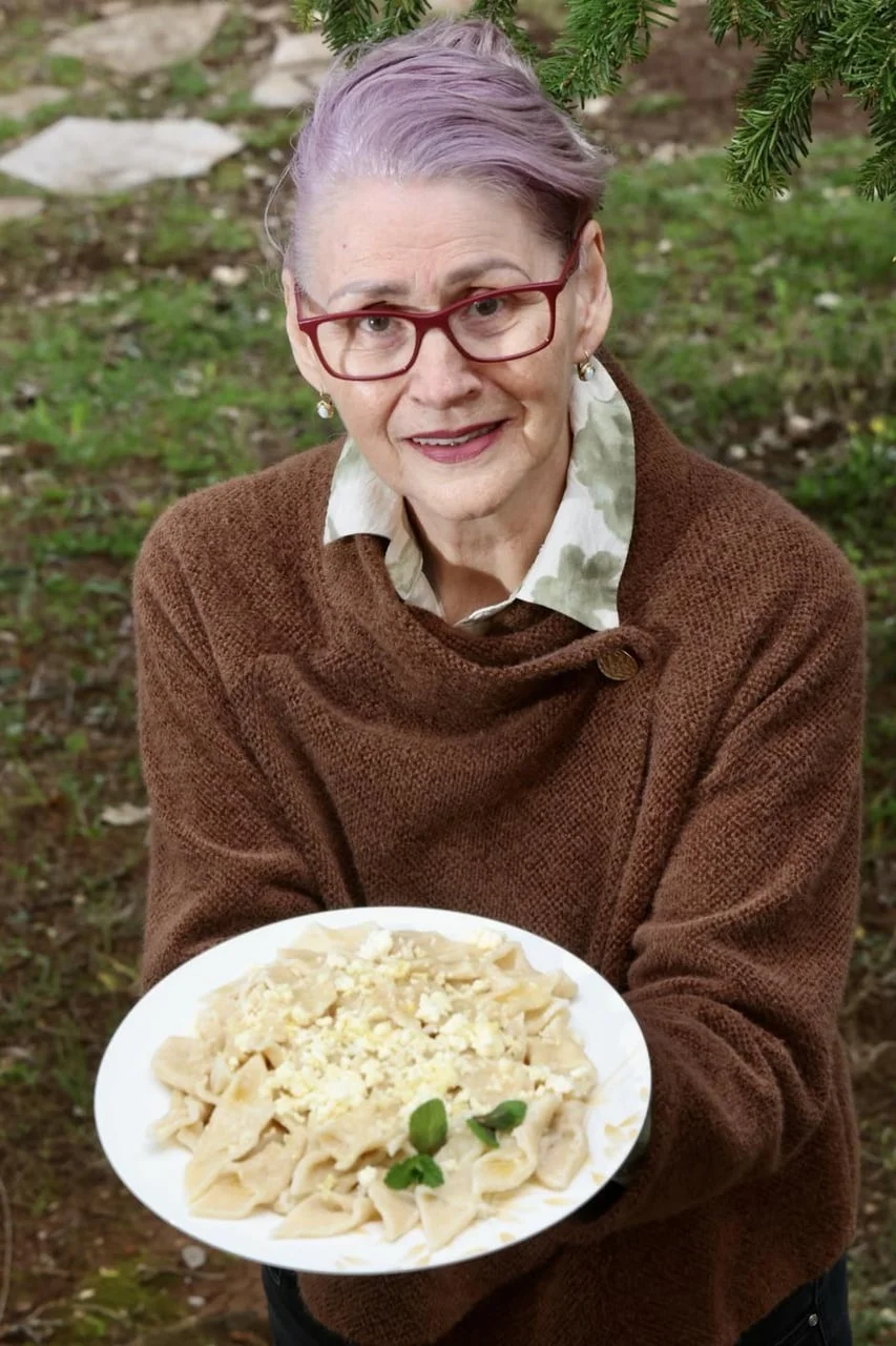 Starija žena s naočalama drži tanjur s domaćom tjesteninom i sirom