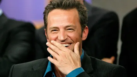 Nasmijani Matthew Perry s rukom preko usta tijekom javnog događaja.