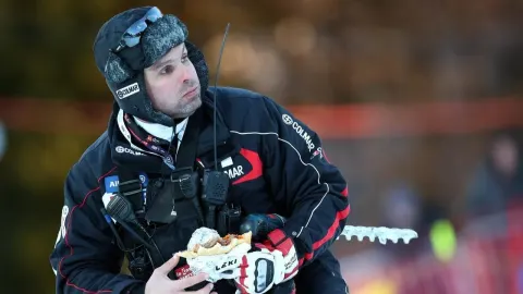 Vedran Pavlek u skijaškoj opremi s motorolom i sendvičem na skijaškoj stazi.