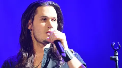 Dino Jelusić pjeva na pozornici s mikrofonom u ruci