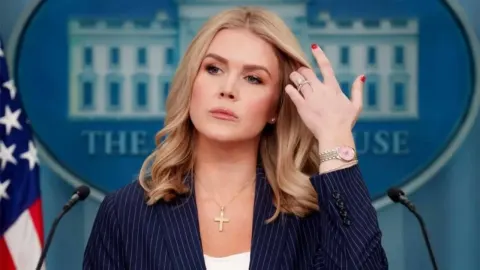 Glasnogovornica Bijele kuće ispred službenog logotipa tijekom brifinga.