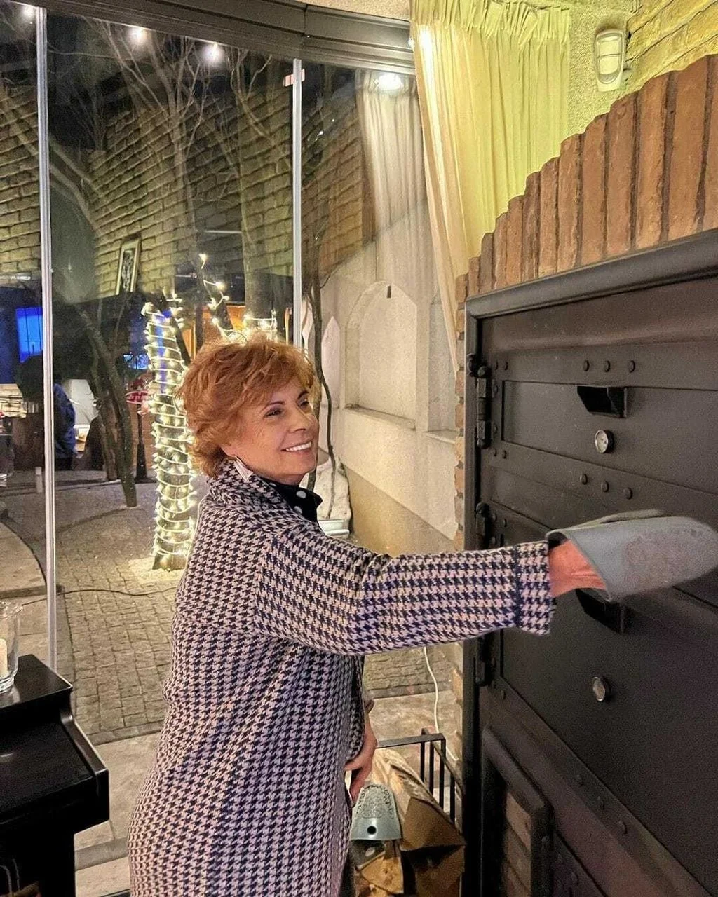 Nasmijana žena pored velike krušne peći u modernoj kuhinji