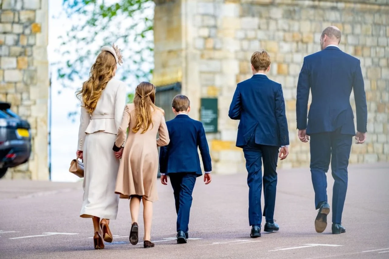 Leđa princa Williama, Kate i djece dok se udaljavaju cestom.