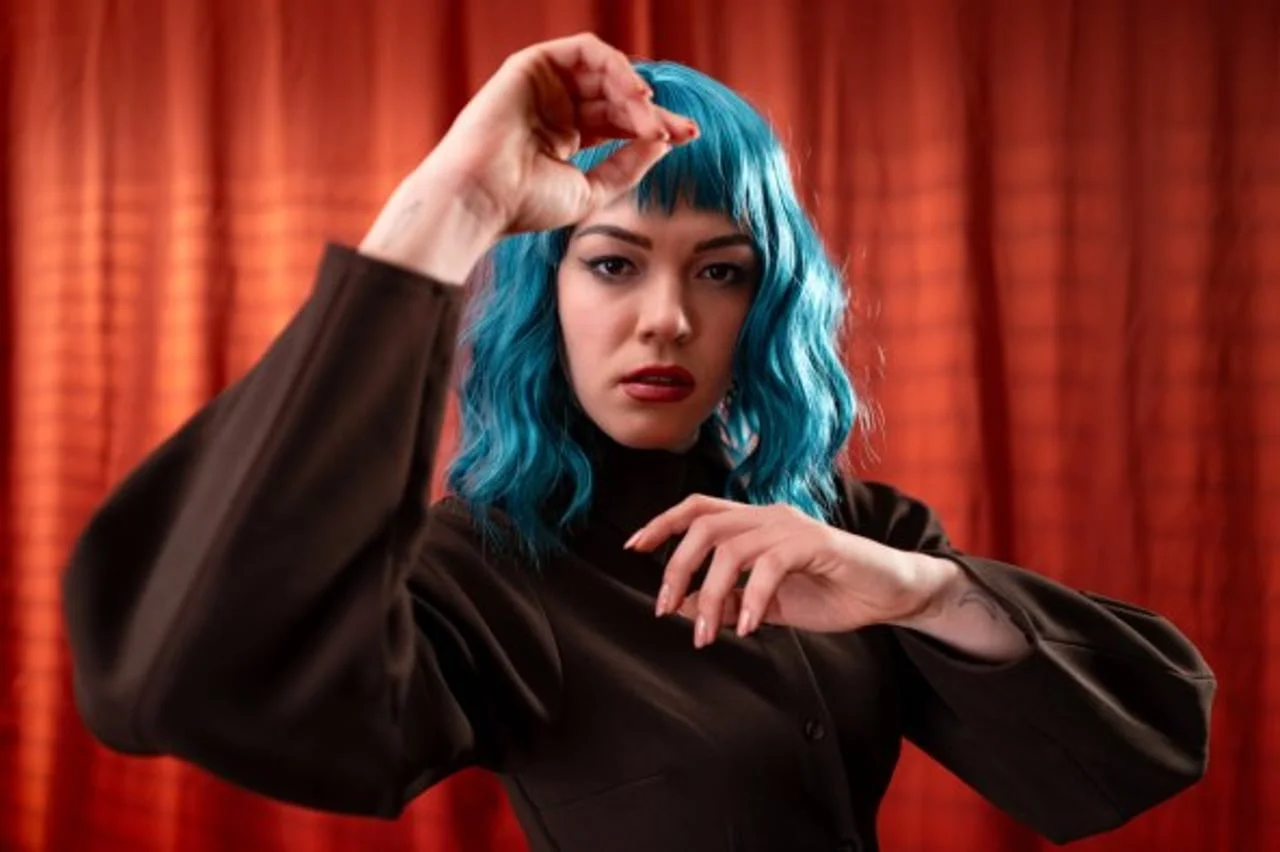 Pjevačica Gina Damjanović s plavom kosom ispred crvene zavjese