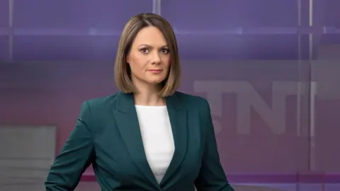 Novinarka Nataša Božić Šarić u tamnozelenom sakou ispred televizijskog studija.