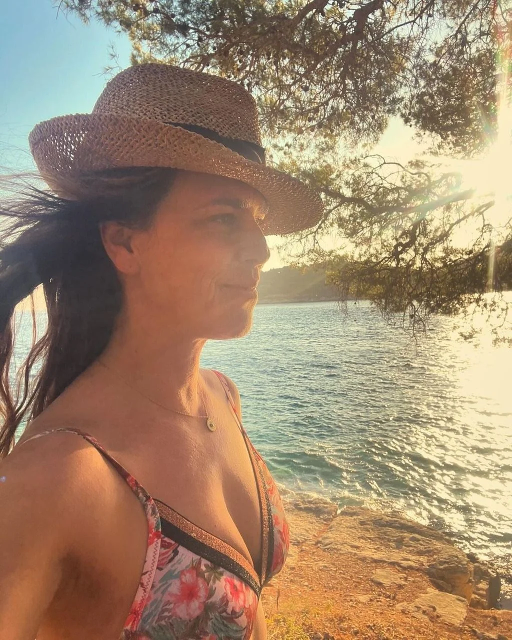 Profil Ane Maras Harmander sa šeširom uz morsku obalu u suton