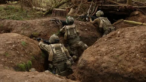 Naoružani vojnici u kamuflažnim uniformama drže položaje u zemljanyim rovovima.