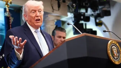 Donald Trump govori za govornicom s predsjedničkim pečatom SAD-a.