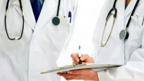 Dva liječnika u bijelim kutama sa stetoskopima i medicinskom dokumentacijom.