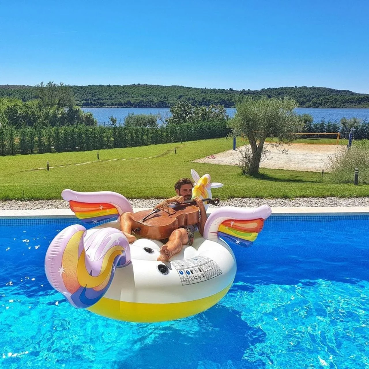 Glazbenik svira violončelo na gumenom jednorogu u bazenu