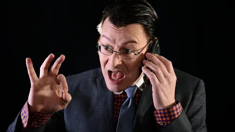 Muškarac u odijelu agresivno razgovara na mobitel