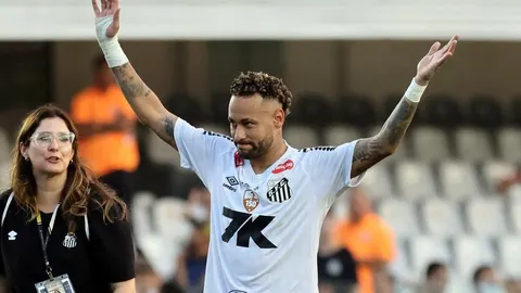 Neymar u bijelom dresu s podignutim rukama na nogometnom stadionu.