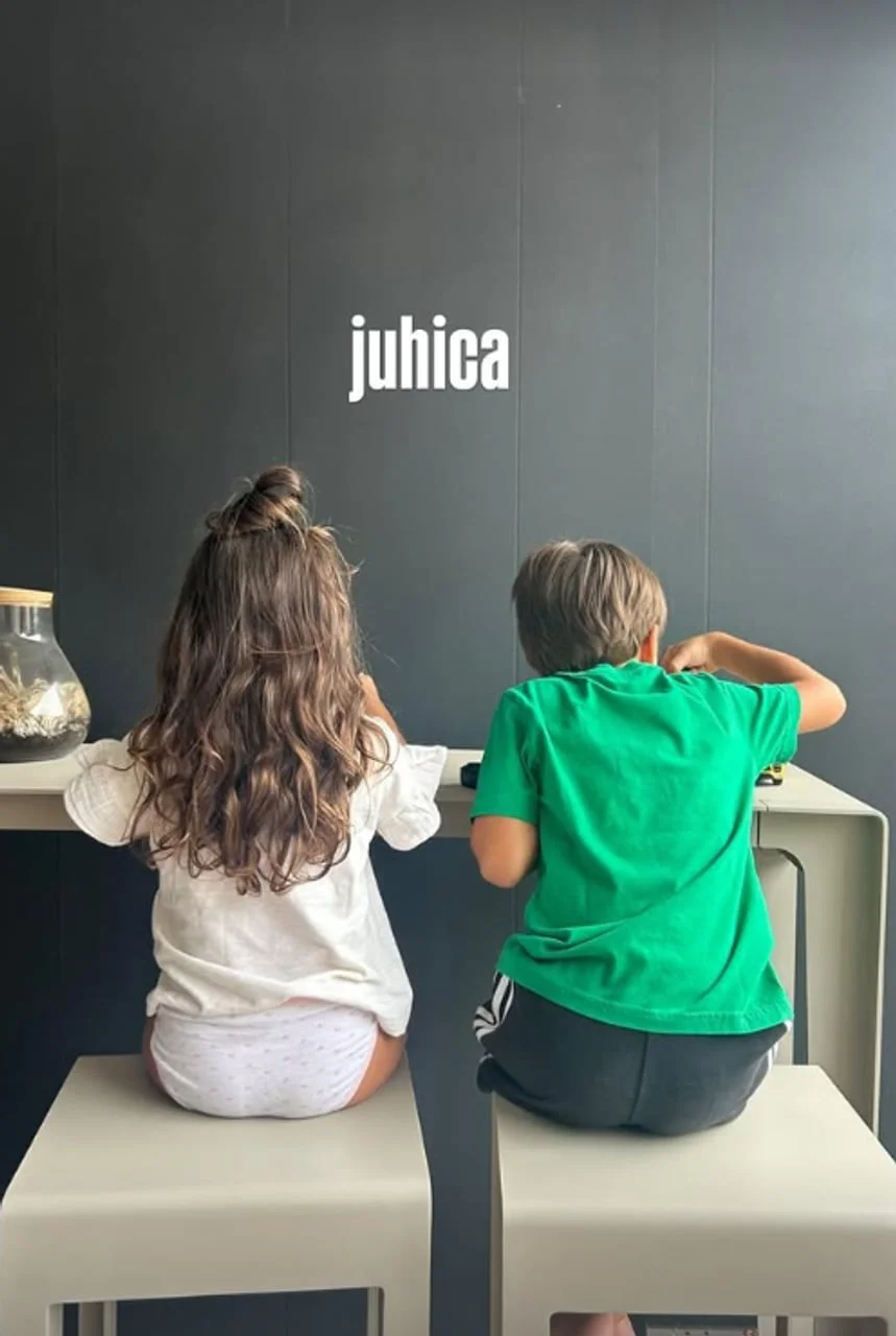 Dvoje male djece sjede za stolom okrenuti leđima prema kameri.