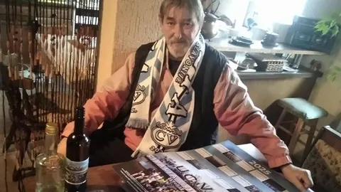 Ivan Budinčević sa šalom vinkovačke Cibalije sjedi za stolom u svom domu.