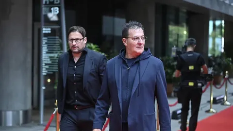 Damir Mišković u plavom sakou s kapuljačom hoda ispred zgrade