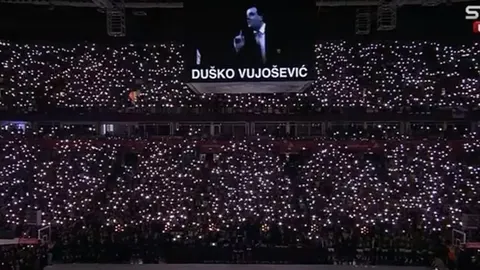 Prepuna dvorana s upaljenim svjetlima mobitela i slikom Duška Vujoševića na ekranu.