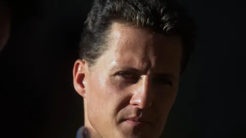 Portret Michaela Schumachera s ozbiljnim izrazom lica na tamnoj pozadini.