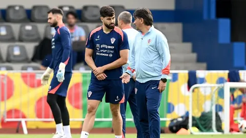 Joško Gvardiol i Zlatko Dalić razgovaraju na nogometnom terenu tijekom treninga.