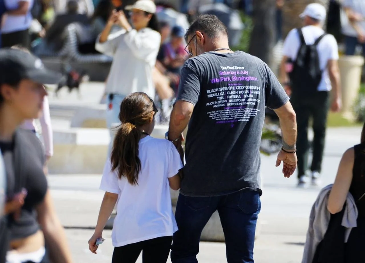 Pogled s leđa na Slavena Bilića koji drži kćer za ruku u šetnji gradom.