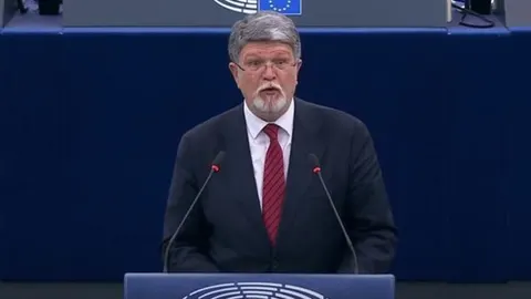 Govornik na govornici Europskog parlamenta s plavom pozadinom