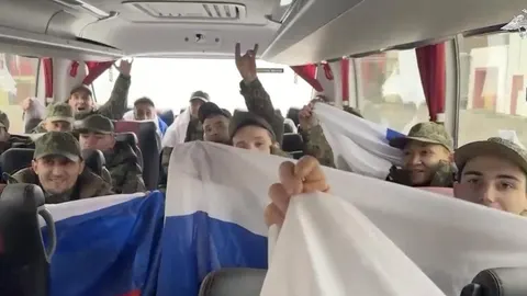 Vojnici u autobusu drže ruske zastave tijekom razmjene zarobljenika