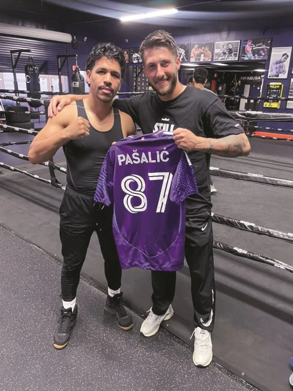 Dvojica muškaraca drže ljubičasti sportski dres s brojem 87