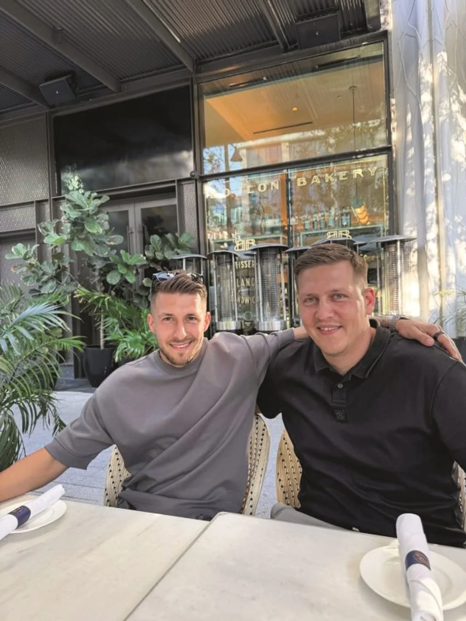 Dva muškarca sjede za stolom na terasi restorana